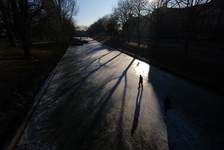 900043 Afbeelding van een schaatser in tegenlicht op de bevroren Stadsbuitengracht langs de Catharijnesingel te ...